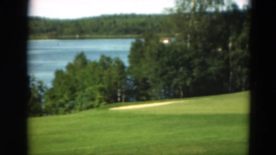 Lakeside golf-course fairway in Duluth, Minnesota, with sand trap, trees, and dark foreground framing from the filming position.