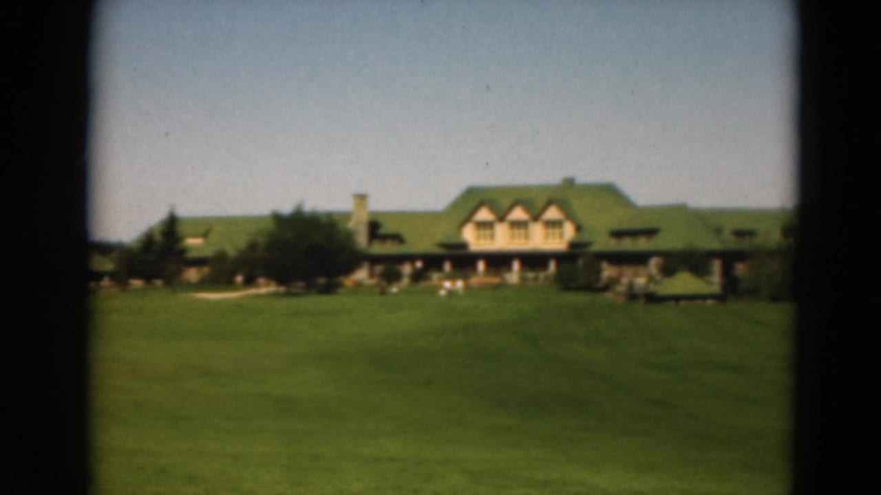 1975 Duluth golf course view with a green-roofed clubhouse beyond an open fairway and trees.