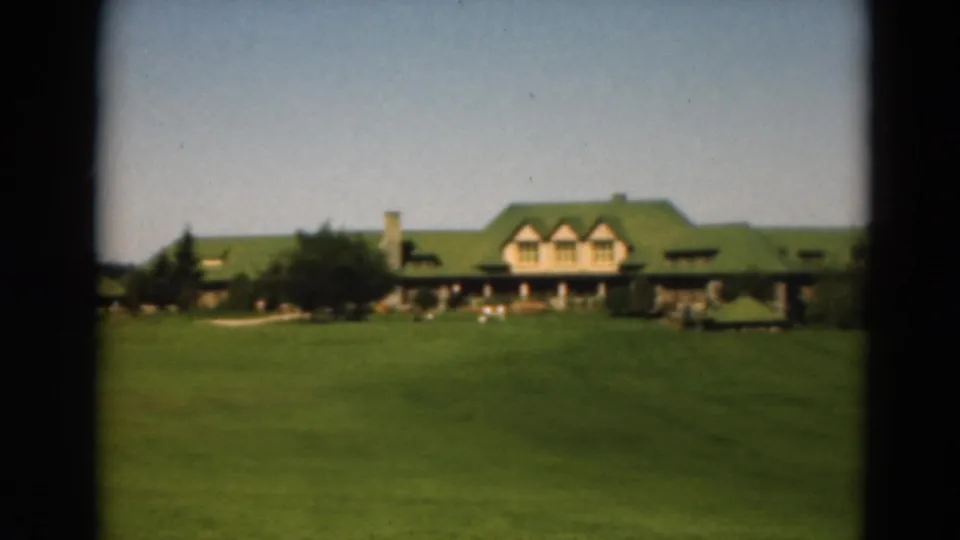 1975 Duluth golf course view with a green-roofed clubhouse beyond an open fairway and trees.