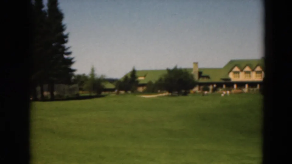 A 1975 Duluth golf course frame shows the clubhouse at right, pines at center, and open fairway in front.