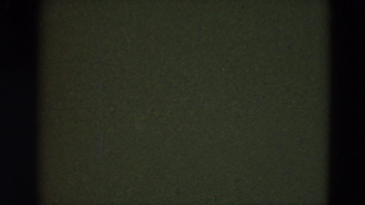 A mostly obscured 8mm frame with dark gate edges and greenish film area, suggesting camera movement or an in-between exposure.