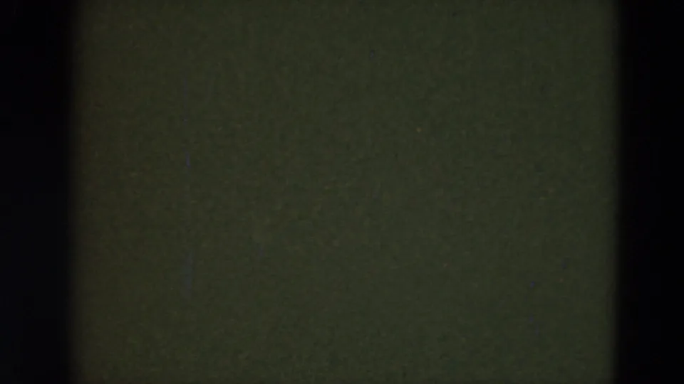 A mostly obscured 8mm frame with dark gate edges and greenish film area, suggesting camera movement or an in-between exposure.