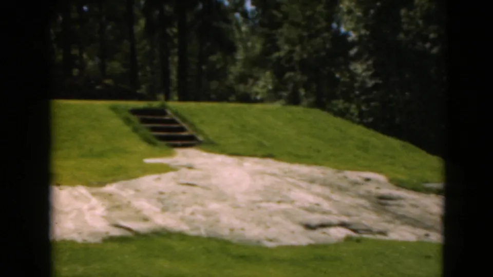 1975 Duluth 8mm frame with the sand trap filling the foreground and steps rising through the green toward trees.