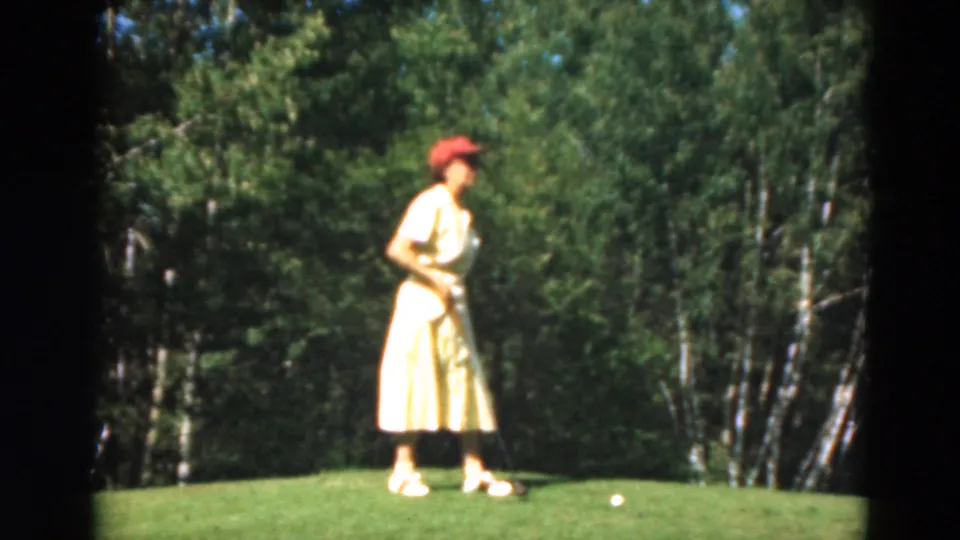 The 1975 Duluth footage shows the woman holding her club on a sunlit green with birch-like trees in the background.