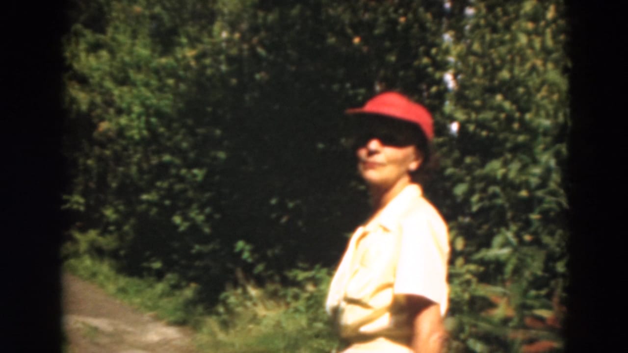 Woman in a red cap standing near a wooded path.