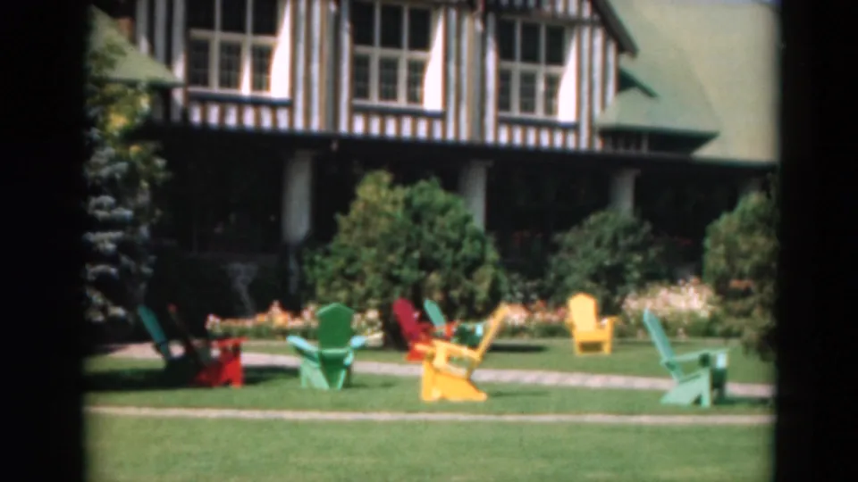Duluth 1975 resort lawn with Adirondack-style chairs, shrubs, flower beds, and a half-timbered building facade.