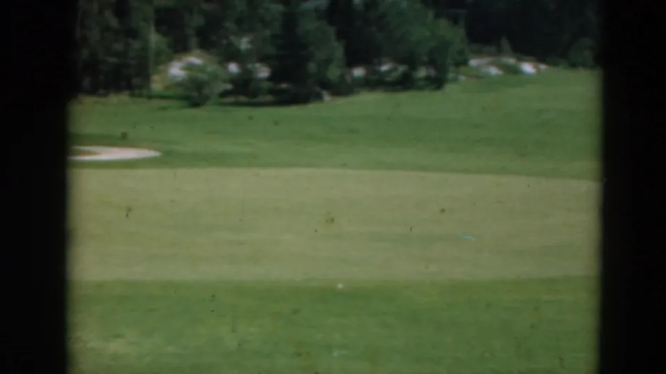 1975 Duluth golf-course frame with green grass, sand traps, and trees, framed by dark scanned-film borders.