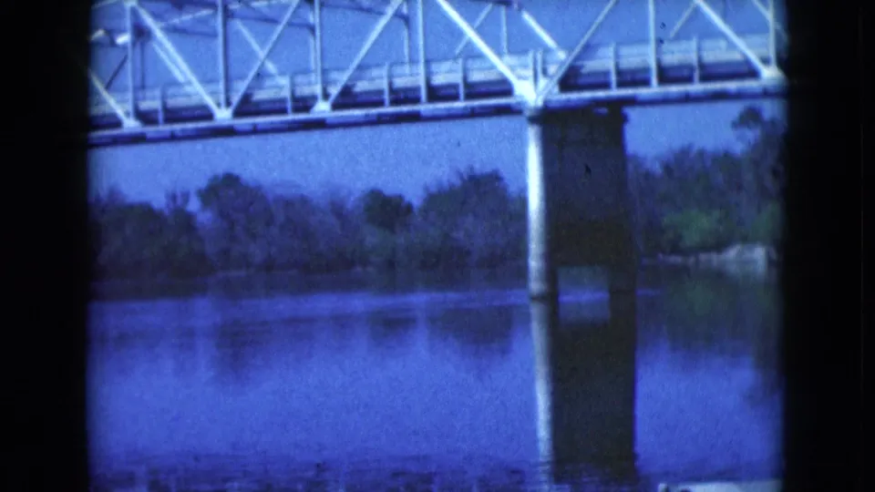 1975 Florida 8mm frame with the bridge span crossing the top of the view above calm reflective water.