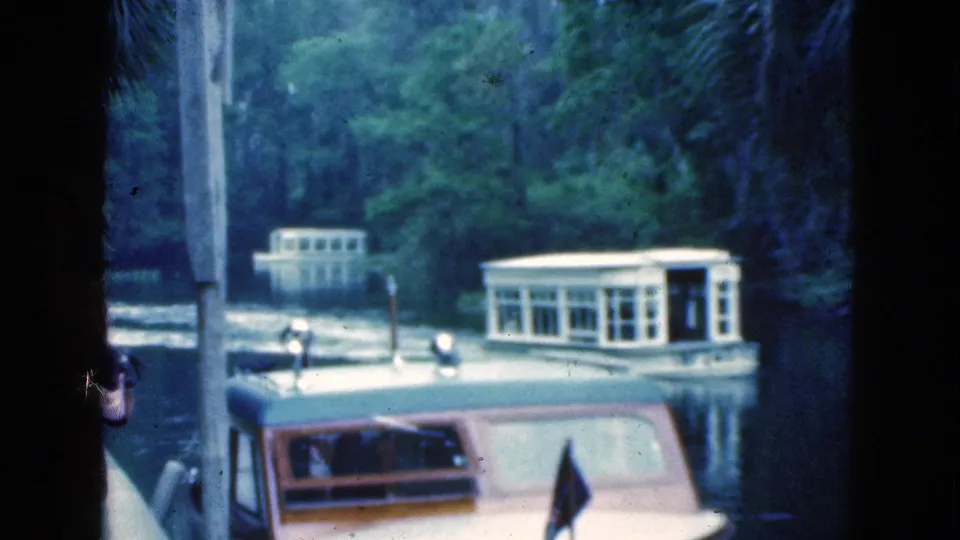 The frame shows the woman partly out of view at a Florida dock, with a white ferry-style boat and a cabin boat on the lagoon.