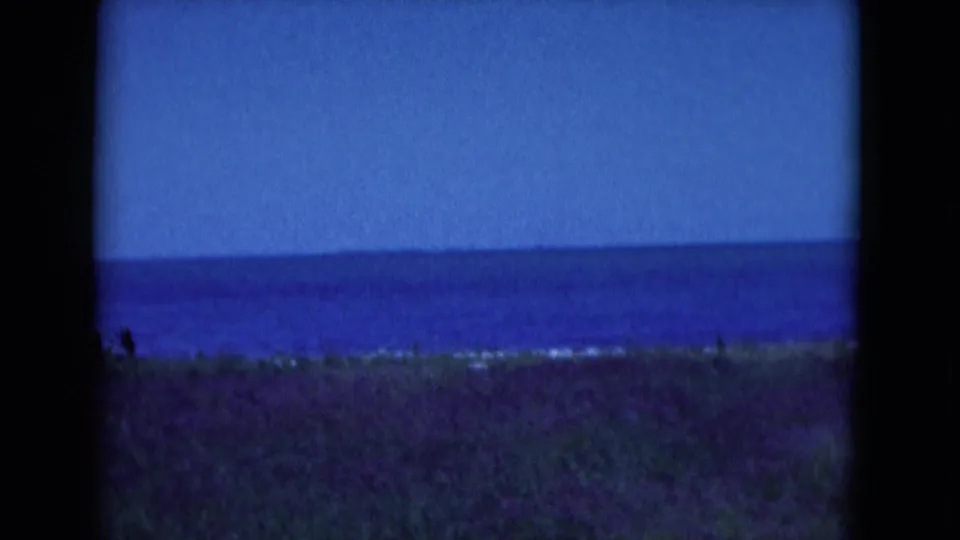 Florida coastal view from the 1975 8mm clip, with blue ocean, low horizon, grassy foreground, and soft home-movie exposure.