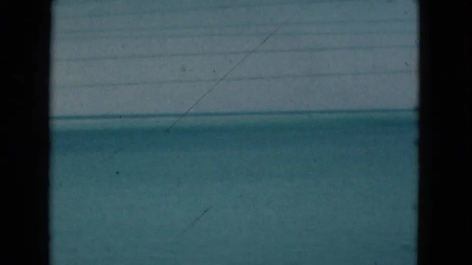 1975 Florida 8mm frame of open blue water, with visible scratches, grain, exposure falloff, and dark film borders.