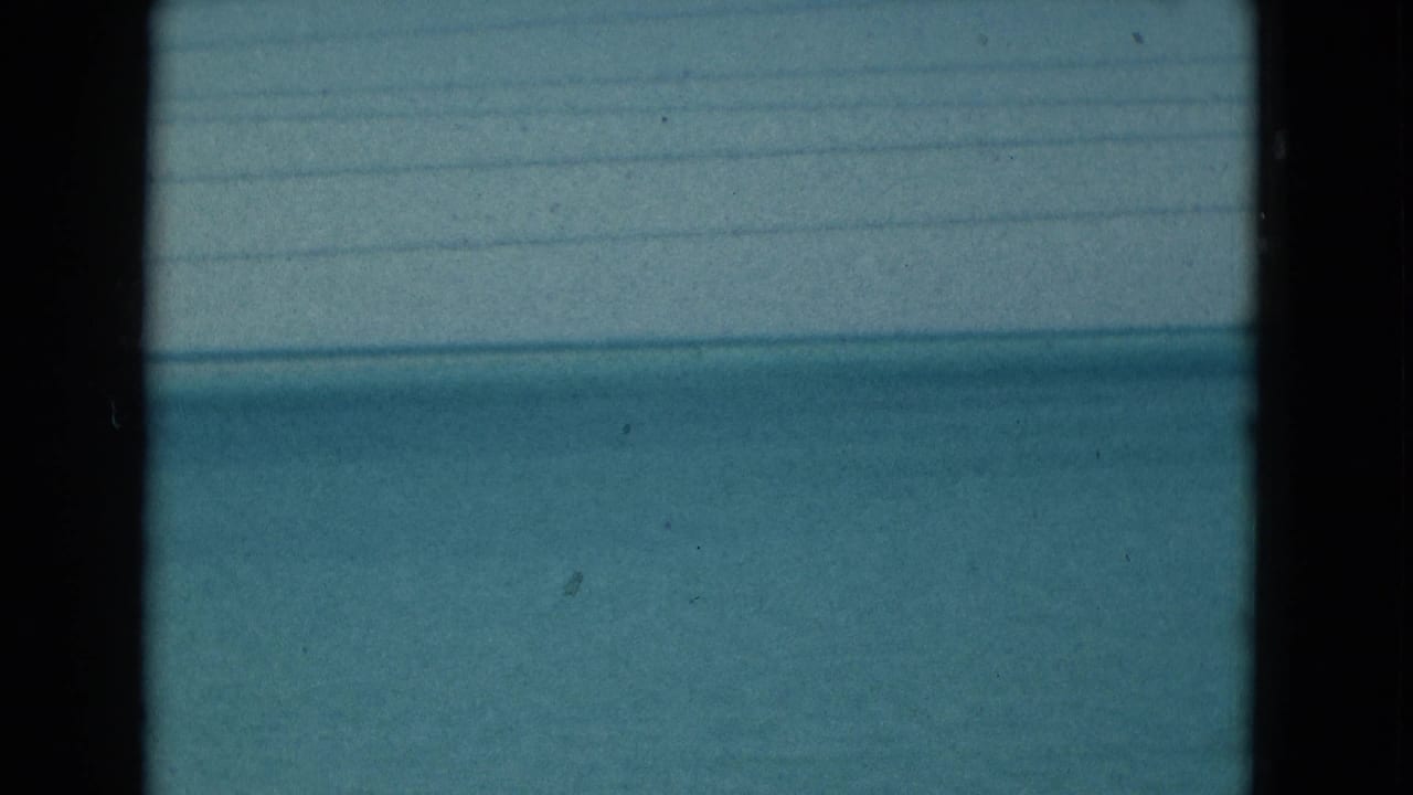 Archival 8mm frame of Florida ocean and sky, with dark vertical obstructions and faint horizontal lines across the view.