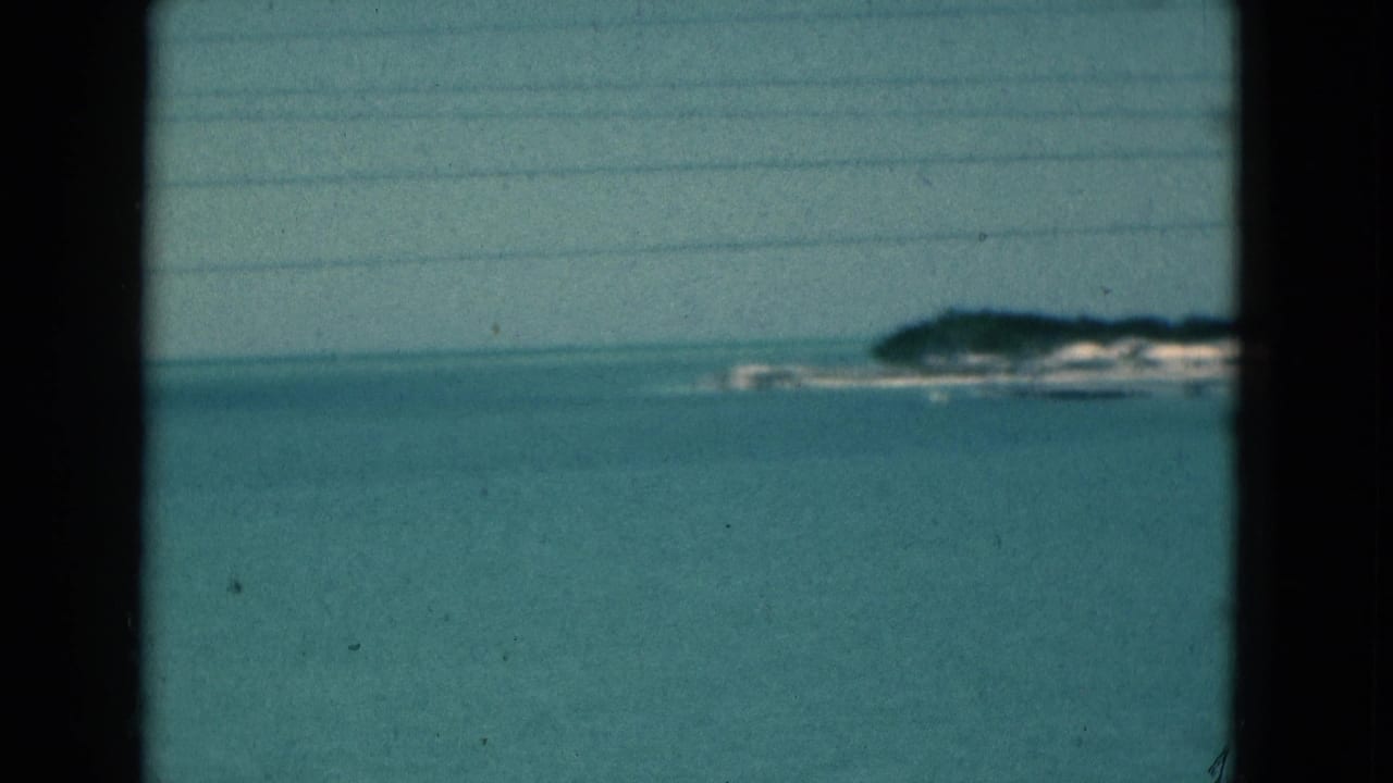 Calm blue-green water and a hazy distant shoreline framed by dark vertical edges.