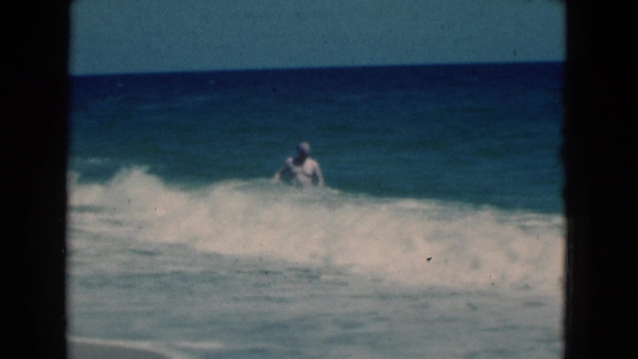 Man partly surrounded by breaking ocean waves near the horizon line.