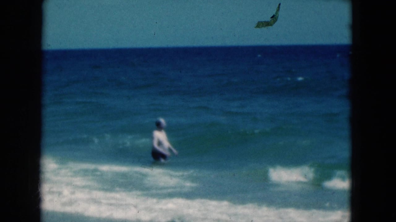 The man continues into the Florida ocean, seen from shore in soft 8mm footage as blue water rises around him.