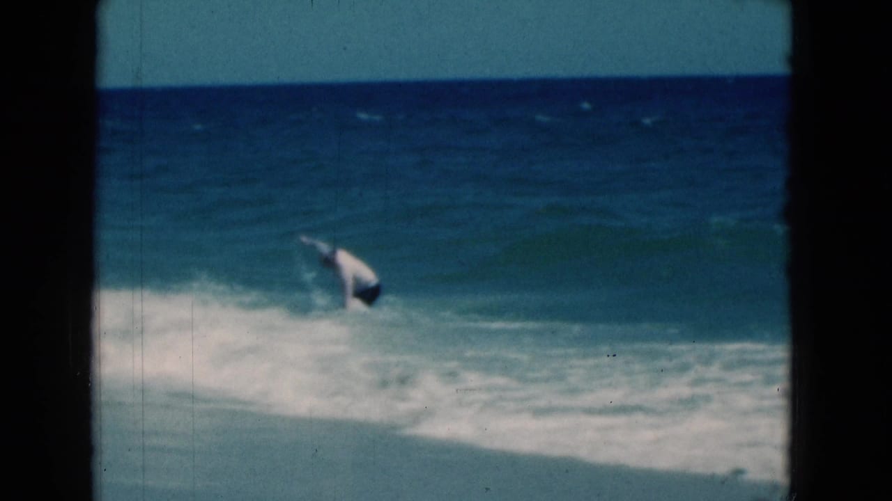 Man bends as a wave breaks around him in the ocean.