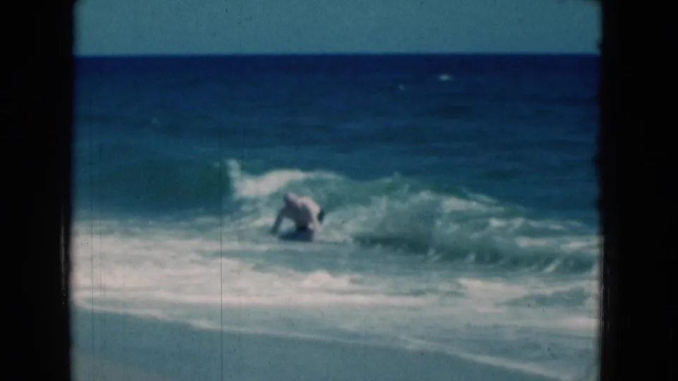The man is down in the foamy surf after being hit by a wave on a Florida beach in 1975 home-movie footage.
