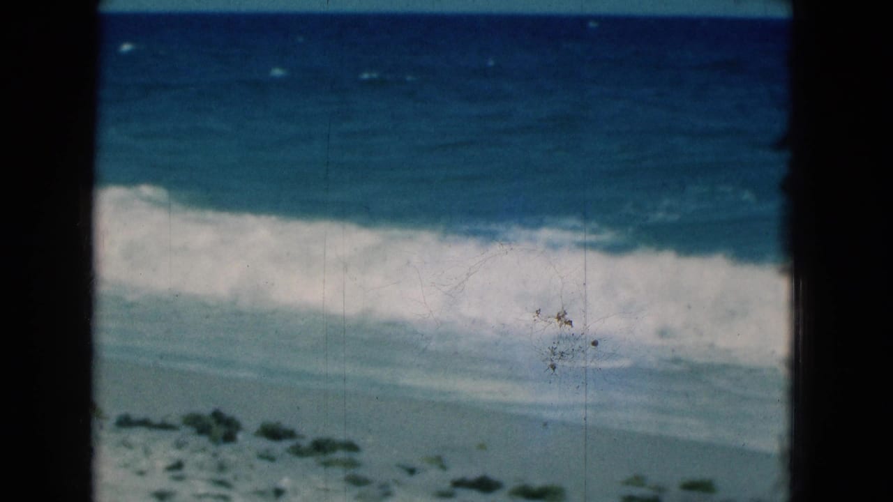 Blue ocean waves break onto a pale sandy beach behind dark 8mm frame borders.