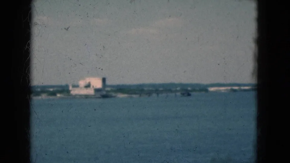1975 Florida waterfront view with a distant building across the water, softened by 8mm grain and exposure.