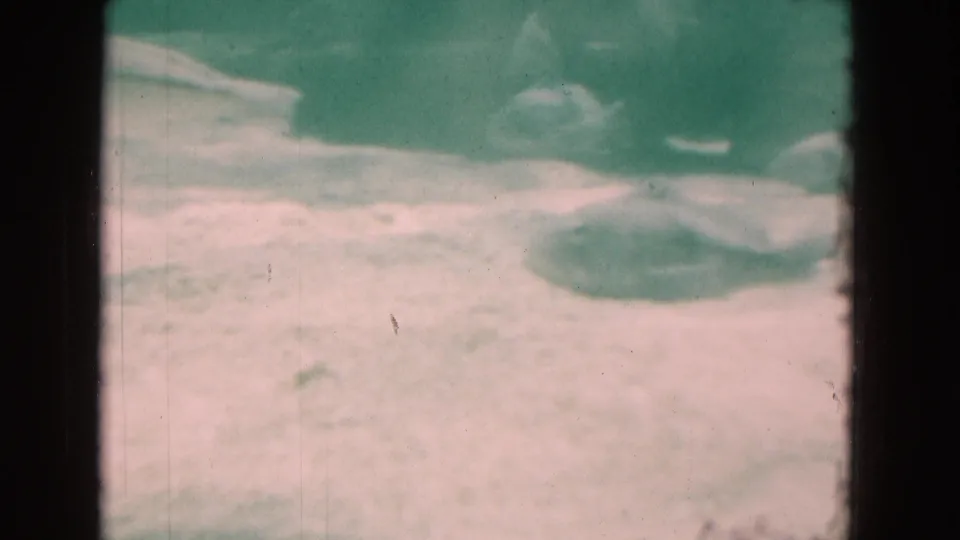 1975 Florida 8mm underwater footage showing soft fish silhouettes near a pale sandy bottom, with heavy green tint and visible frame edge.