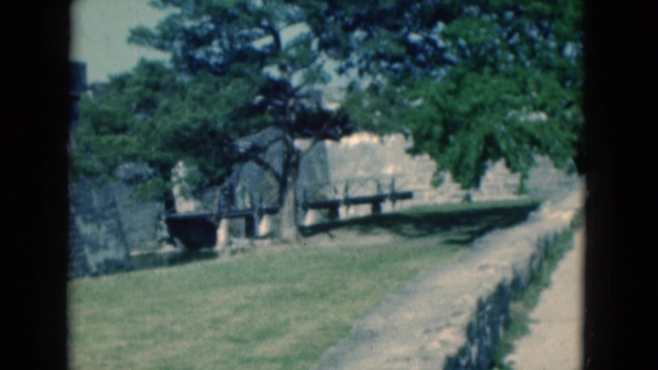 Tree-covered fortress grounds with benches, lawn, path, and stone walls.