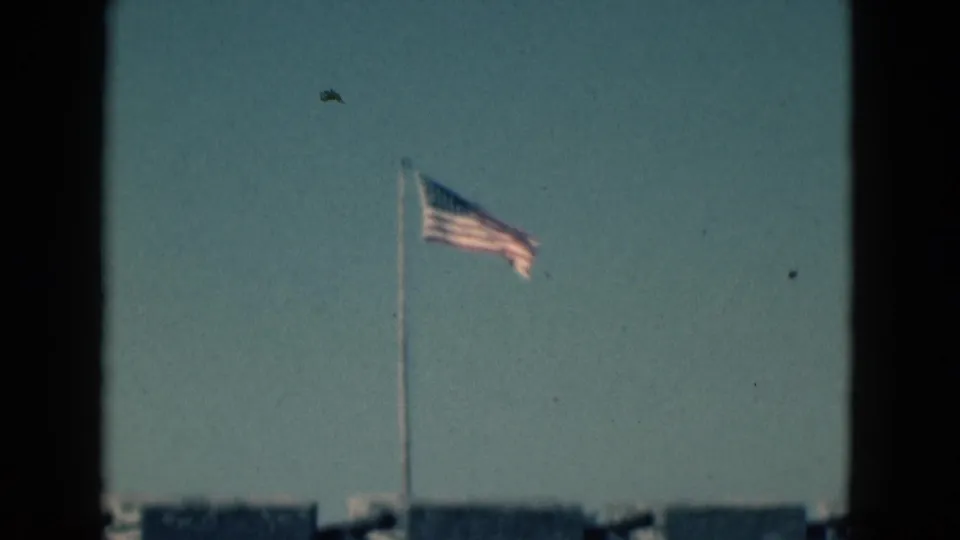 American flag flying against a blue sky above a historic stone fort in the 1975 Florida home-movie footage.