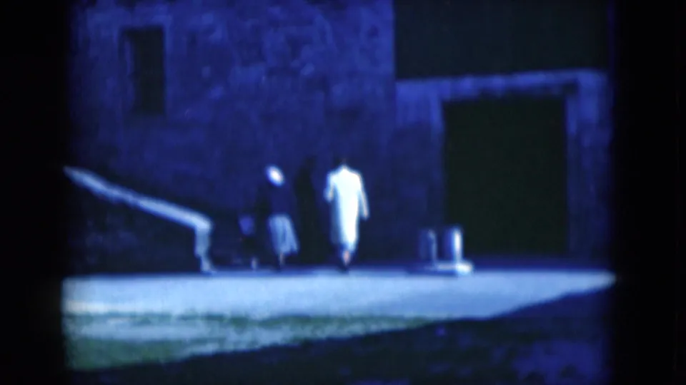 1975 Florida 8mm frame of two visitors in a dim fort courtyard or entrance area beside stone walls.