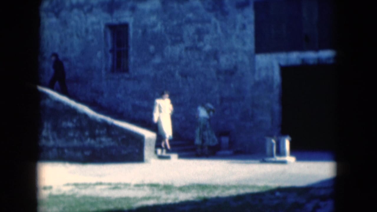 1975 Florida home-movie frame of a woman in a light dress descending stone steps at a historic-looking exterior wall.