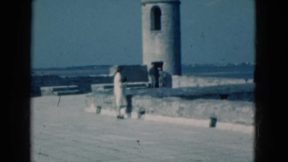 1975 Florida travel frame showing the stone walkway, domed sentry tower, ocean view, and visitors at a historic coastal site.