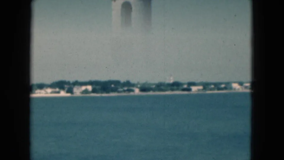 Soft 8mm view across Florida water toward a low distant shoreline, with a faint tower edge at the upper frame.