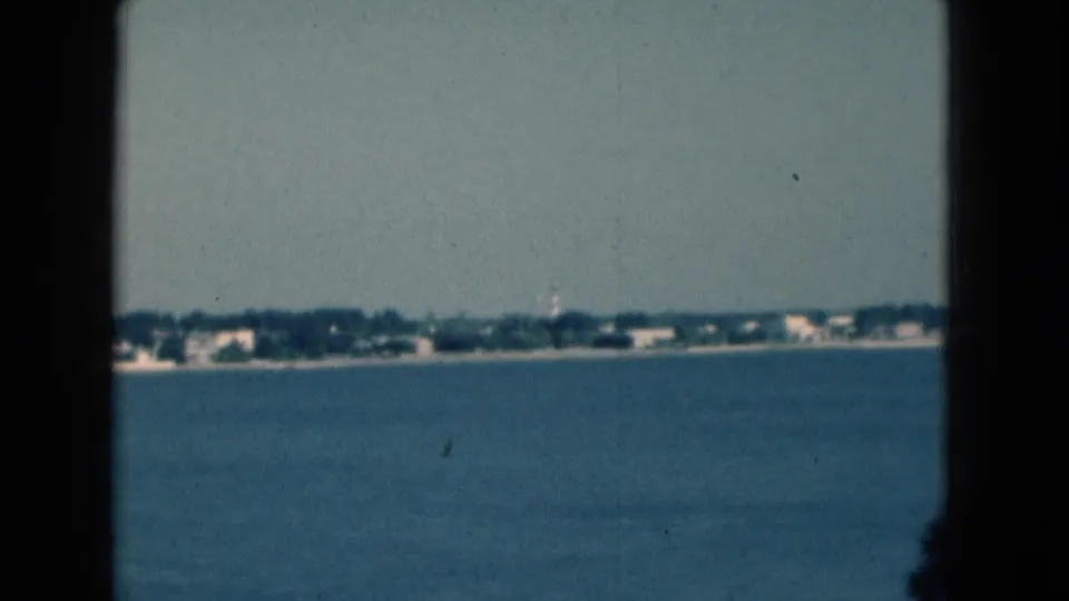 1975 Florida 8mm frame looking across open water toward a low shoreline, with soft focus and visible film edges.