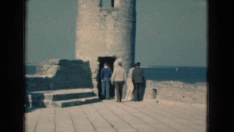 Visitors stand at the entrance of old stone fort ruins on a Florida coast, with water visible behind the site.