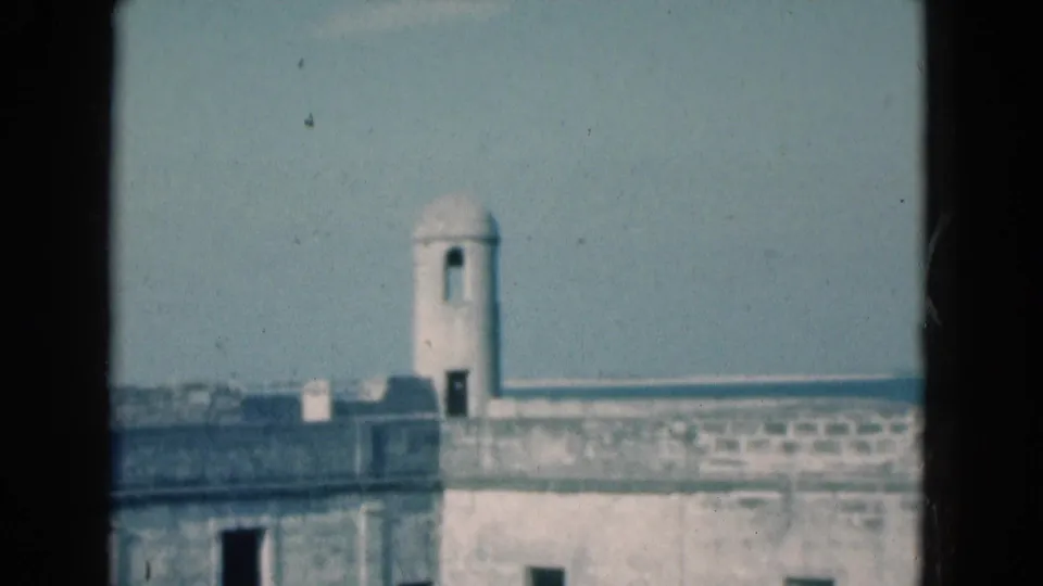 1975 Florida home-movie frame of a small domed turret and stone waterfront wall against blue water.