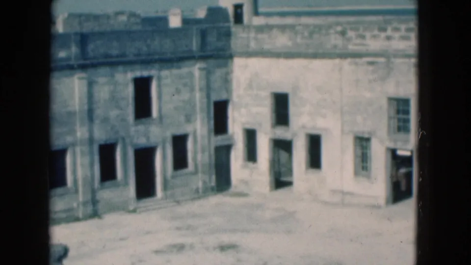 Soft 8mm view of the lower stone fort wall in Florida, with open doorways, small windows, and empty courtyard space.