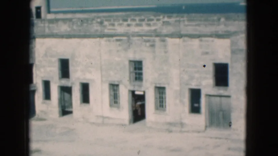 Soft 8mm frame from Florida in 1975 showing the fort wall, open windows and a person in a doorway.