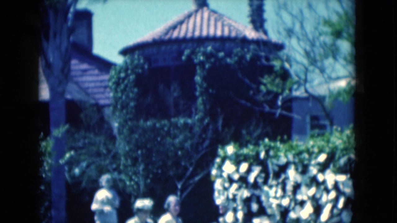 A round ivy-covered building stands behind hedges as visitors appear partly at the bottom of the 1975 Florida garden frame.