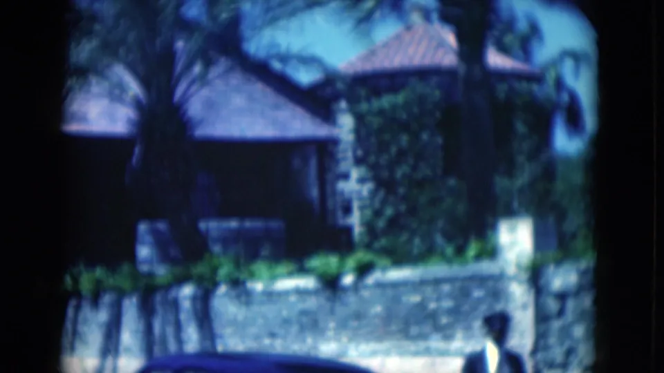 The final 1975 Florida frame shows the stone residence and palms, with a partial passerby visible near the bottom edge.