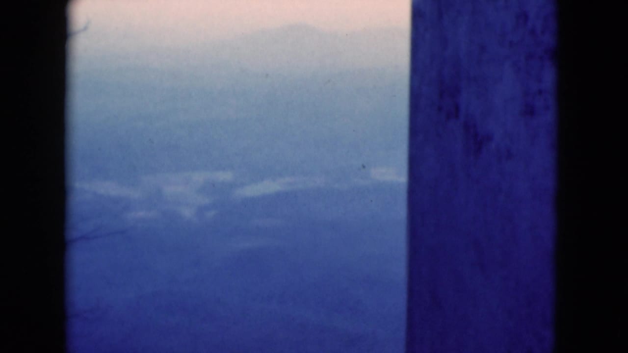 Blue-toned distant mountains seen between dark vertical posts.
