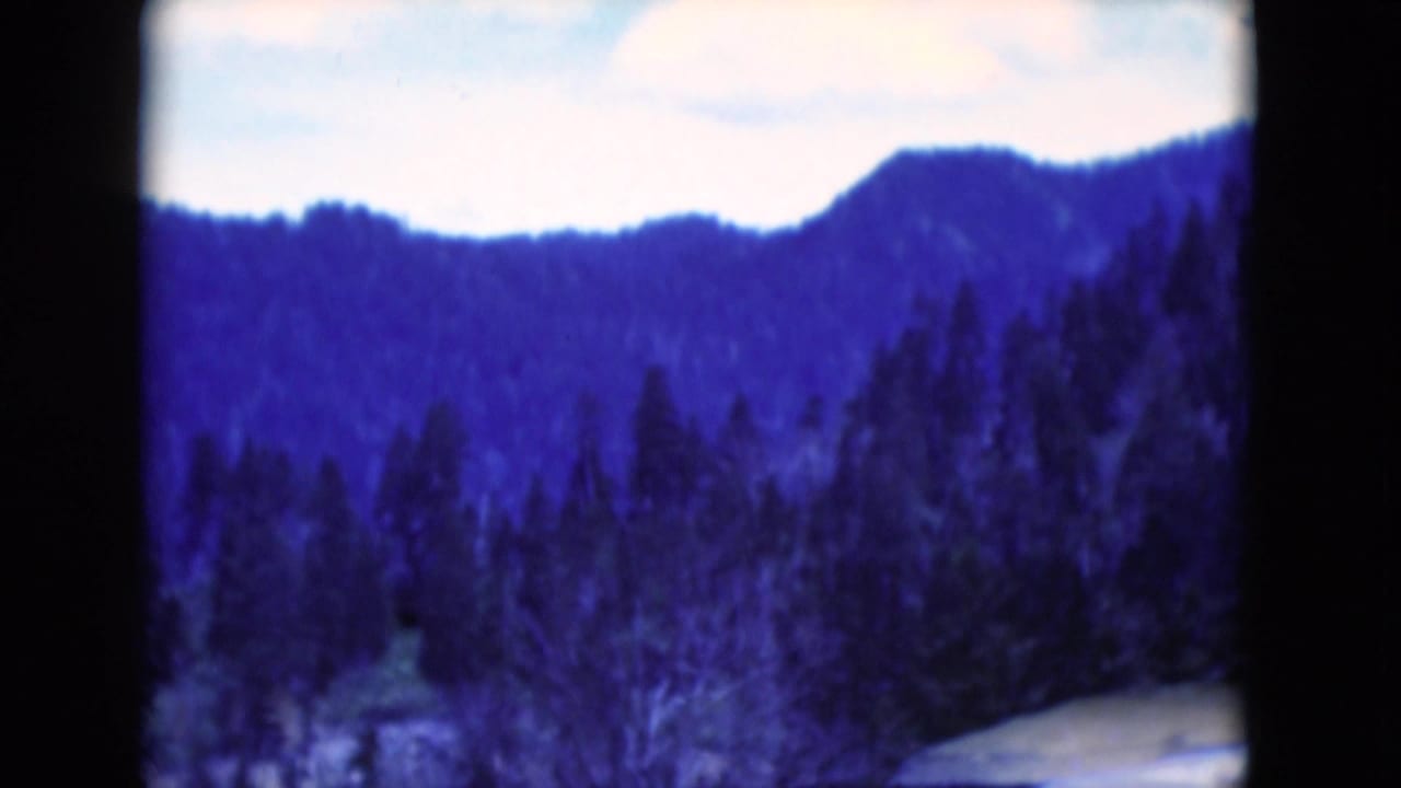 Forested ridge and snowy hillside seen through a blue-tinted 8mm frame.