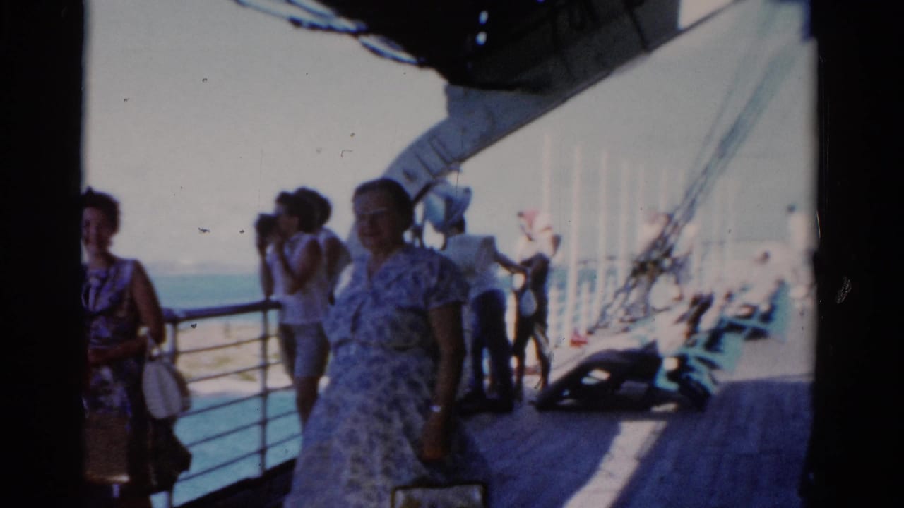Passengers on a boat deck near railings with ocean visible beyond.