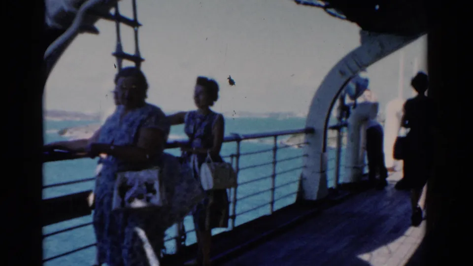 1975 Florida home-movie frame of women on a boat deck beside railings, with ocean views, a ladder, and shaded vessel structure around them.
