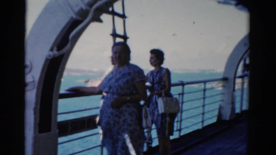 Two women stand near the rail on a 1975 Florida cruise deck while another figure is partly visible near the edge of the frame.