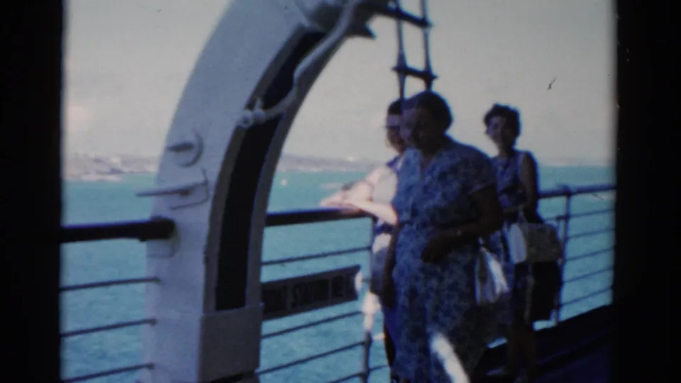 Women passengers on a Florida cruise ship deck stand beside a curved white structure and rail with blue water in the background.