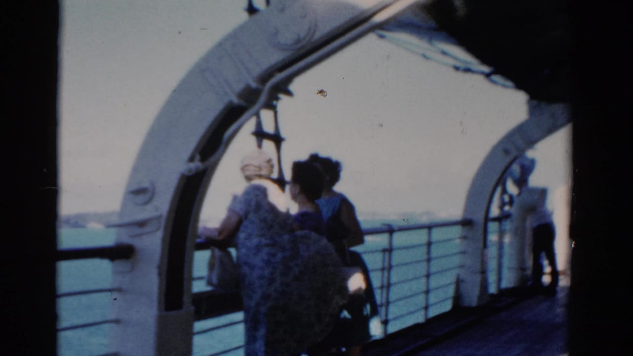 Passengers on a 1975 Florida boat deck stand by the rail with open water and shore in the background.