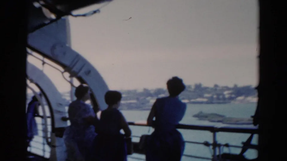 1975 Florida 8mm frame of women on a cruise ship deck watching the water and distant shoreline.