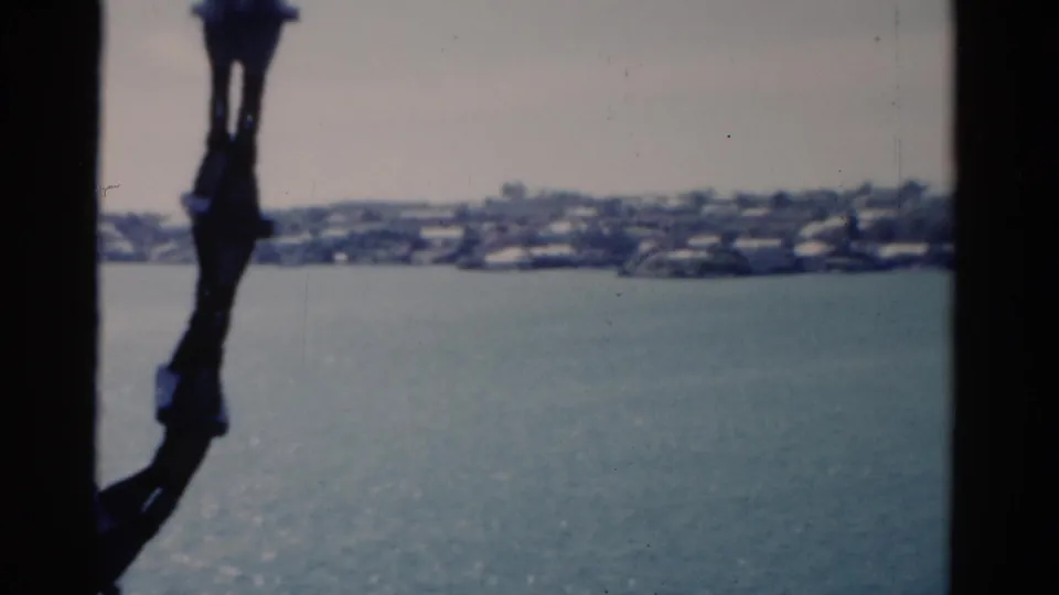 1975 Florida waterfront view across open water, with a dark vessel railing or window frame crossing the foreground.