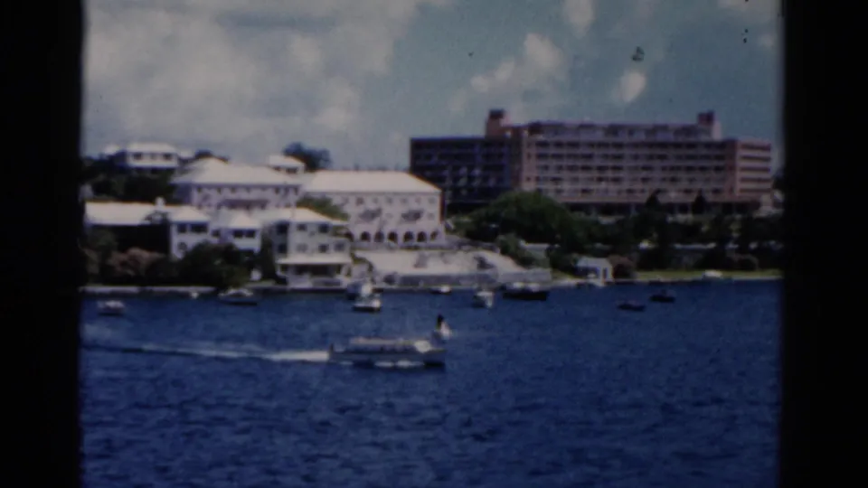 Florida waterfront with white buildings, a large hotel-like structure, small boats, and deep blue water seen from a boat in 1975.