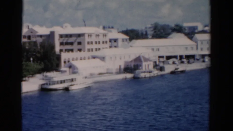 A closer Florida waterfront section shows pale buildings, moored boats, a quay, and deep blue harbor water from a moving boat viewpoint.