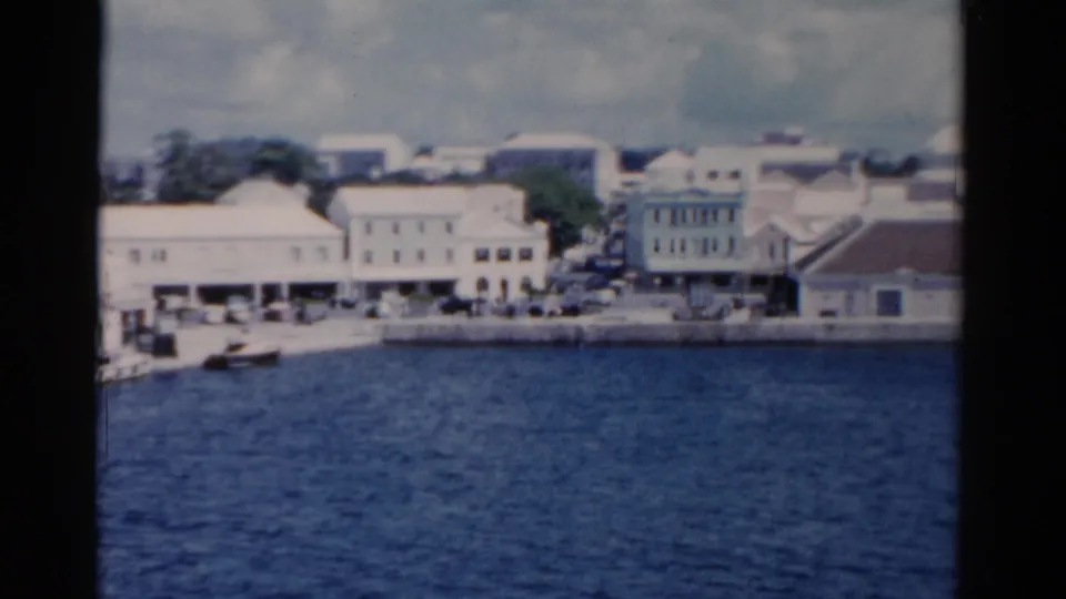 Soft 8mm frame of a Florida waterfront with blue water, low buildings, boats, and distant streetfronts in 1975.