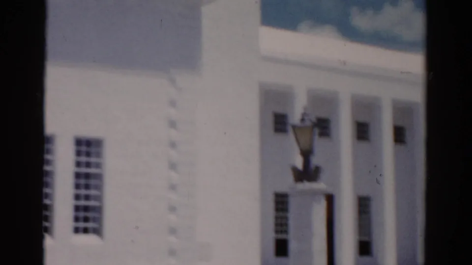 1975 Florida 8mm frame showing a white facade with tall windows, columns, and a decorative lamppost near the entrance.